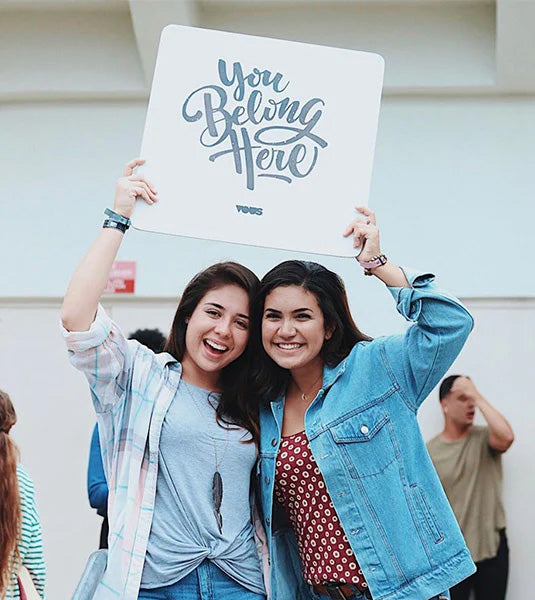 Two friends holding a You Belong Here Popsign